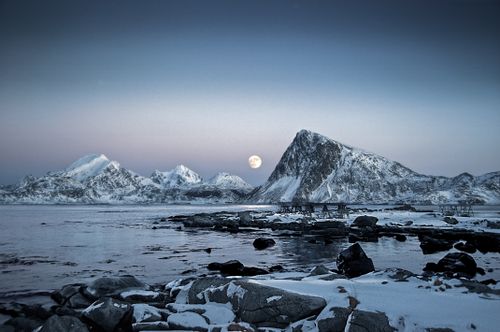 Free Serene winter scene of snowy mountains and a full moon reflected on a calm sea in Nordland. Stock Photo