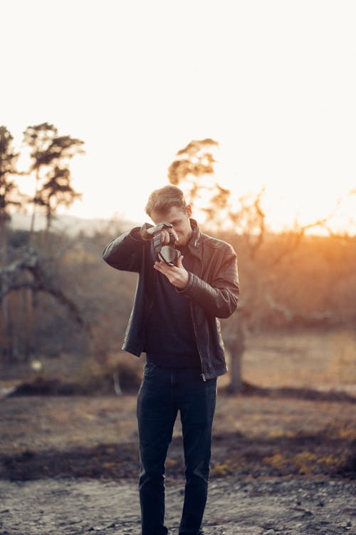 Man in a Leather Jacket Taking a Photo with a Camera