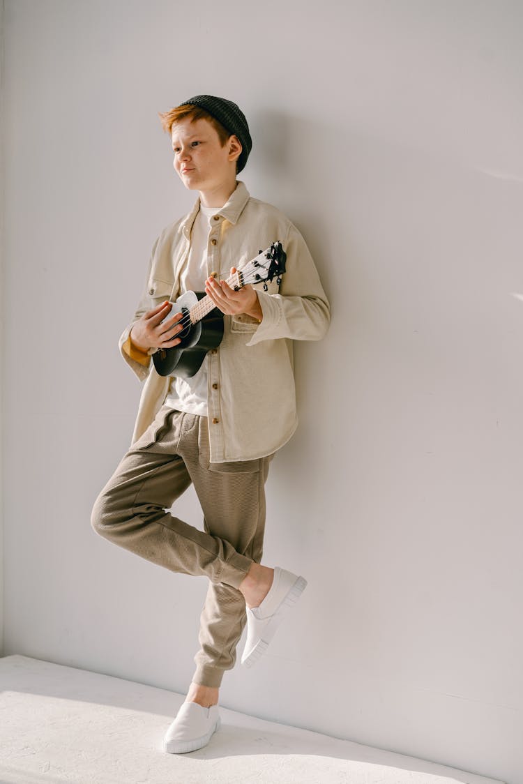 Boy Playing Ukelele While Leaning On A Wall