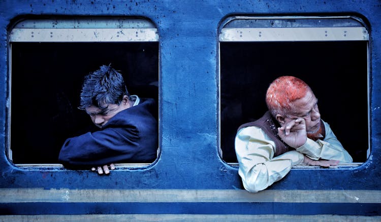 Men Sitting Inside The Train While Looking At The Window