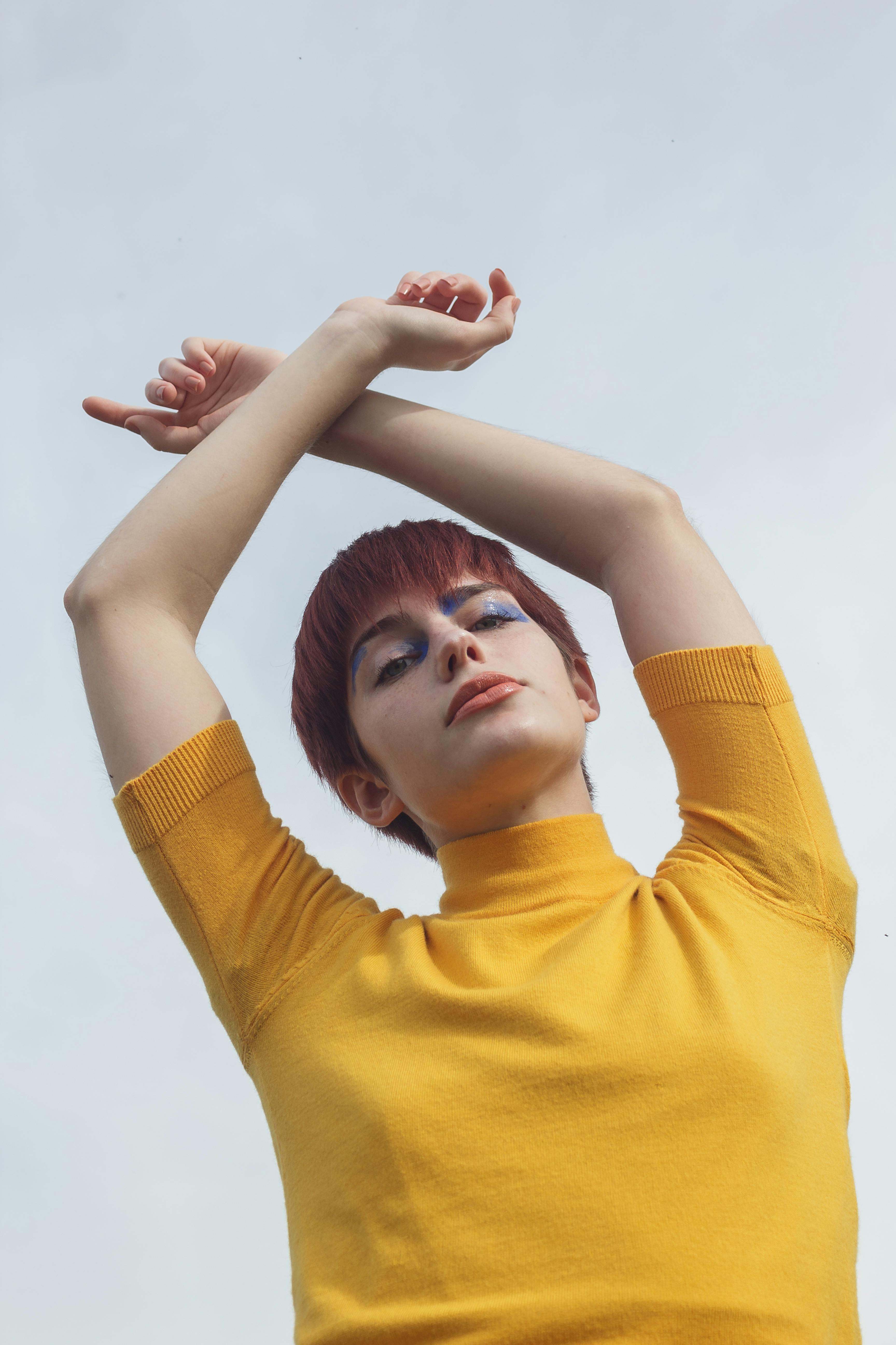 woman in yellow shirt raising her hands