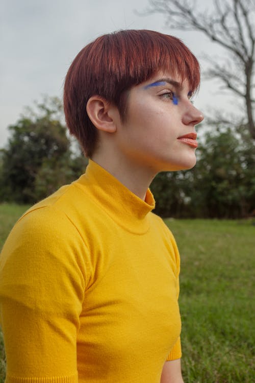 Free Woman in Yellow Crew Neck Shirt Standing on Green Grass Field Stock Photo