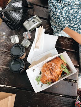 Top view of a delicious outdoor brunch setup with croissants and coffee on a wooden table.