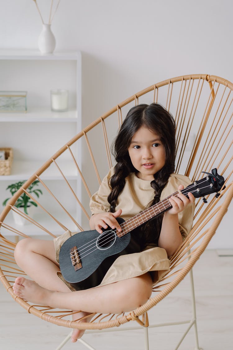 Close-Up Shot Of A Girl Playing Ukelele While Sitting