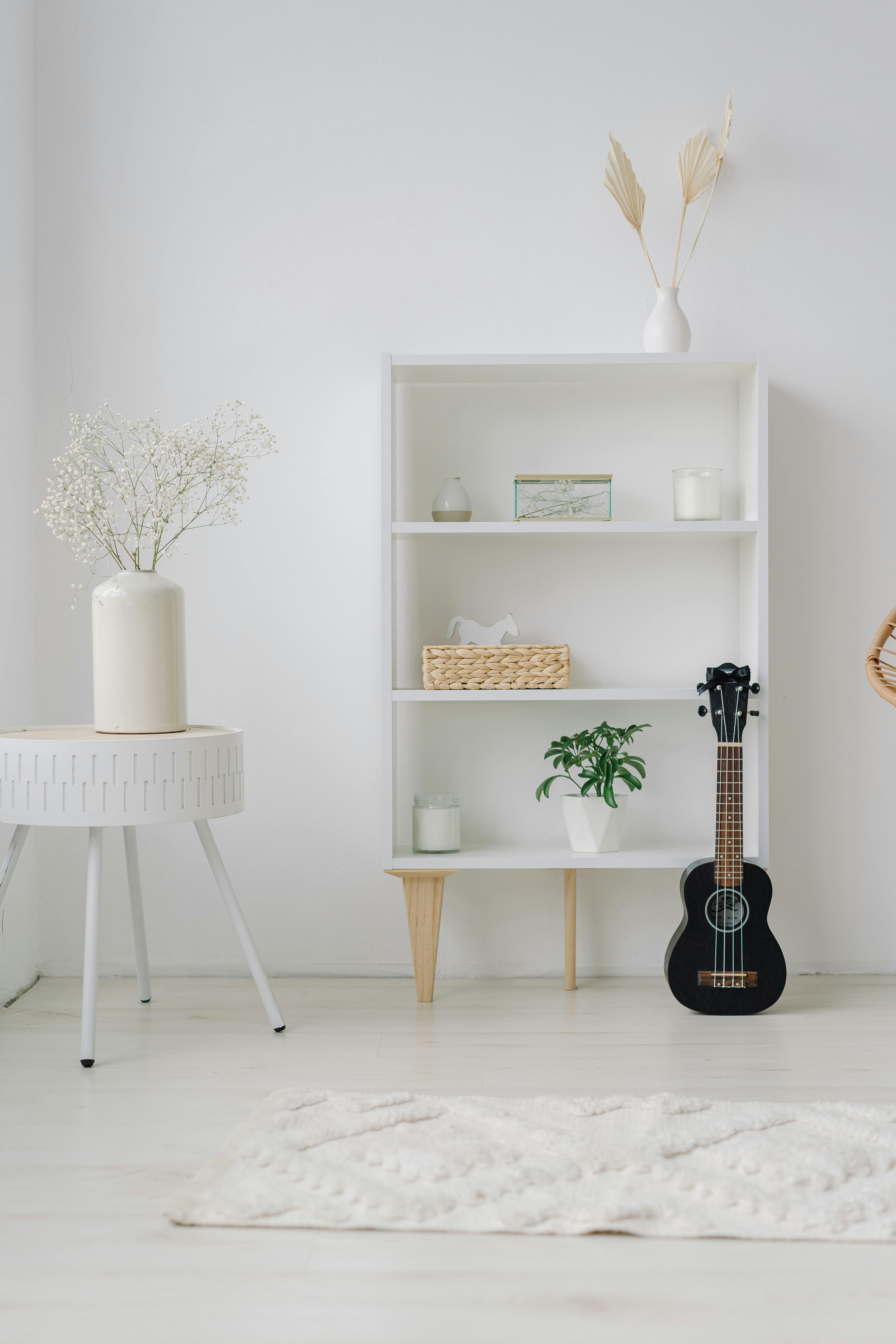 Free Elegant minimalist home decor featuring a ukulele, potted plants, and ceramic vases on a wooden shelf. Stock Photo