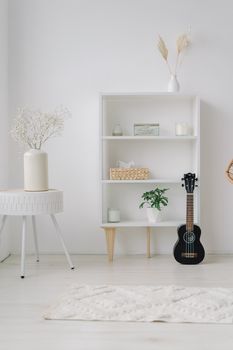 Elegant minimalist home decor featuring a ukulele, potted plants, and ceramic vases on a wooden shelf.