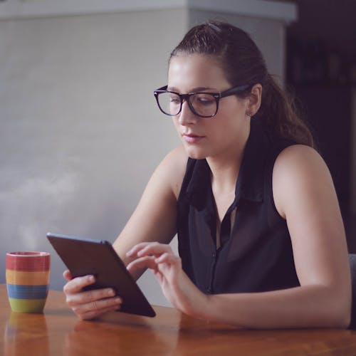 Woman in Black Eyeglasses Using a Tablet