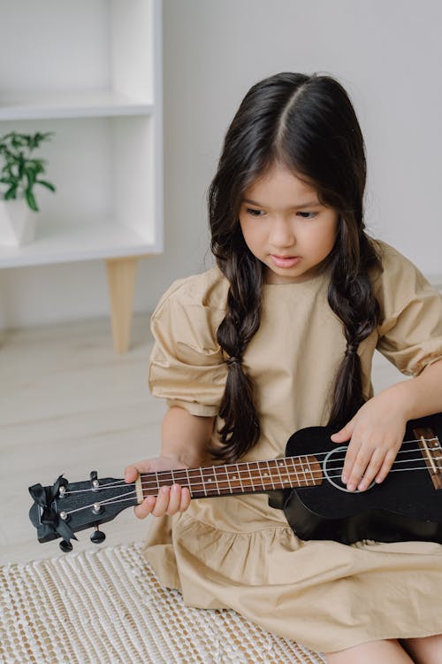 Woman in Brown Coat Playing Guitar