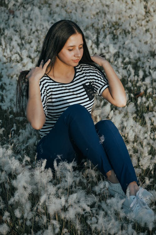 Woman in Stripe Shirt and Sitting on Grass Flowers