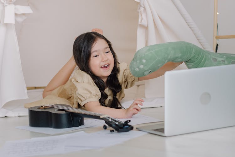 Close-Up Shot Of A Girl Near A Ukelele And Laptop 