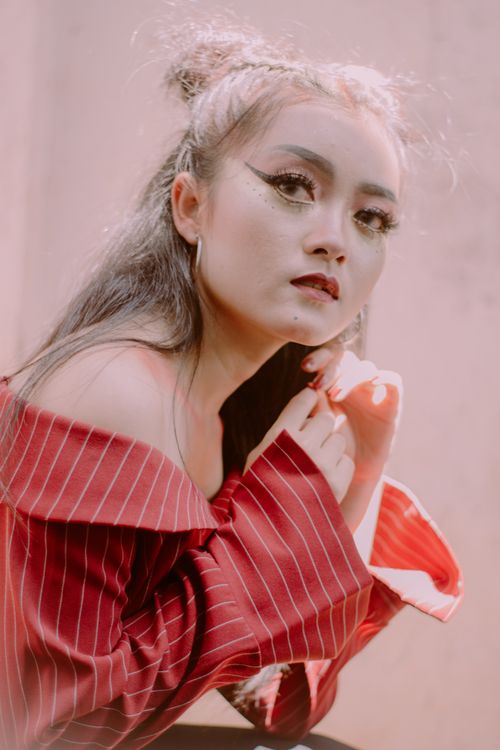 Free Fashionable portrait of a woman with bold makeup and a stylish red outfit, posing with a soft background. Stock Photo