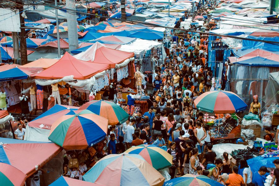 A bustling outdoor market with colourful tents and a crowd of shoppers