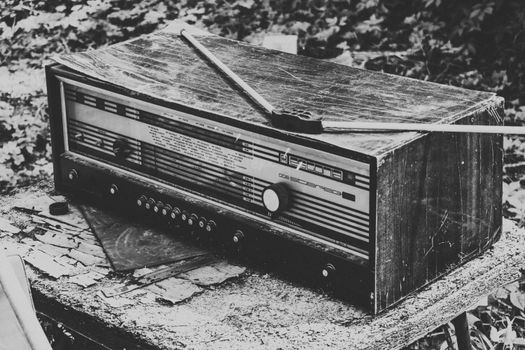 Classic black and white shot of a vintage radio on a rustic, weathered table.