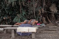 在菲律宾马尼拉，一名妇女正在绿树成荫的公园长凳上休息