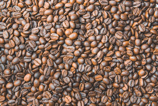 Close-up flat lay of roasted coffee beans showcasing texture and aroma, perfect for coffee themed designs.