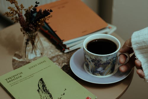 Free Woman having cup of fragrant coffee at table with book Stock Photo