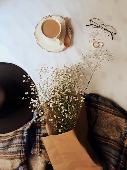 Flowers Wrapped in Textile Beside a Cup of Coffee on a Saucer