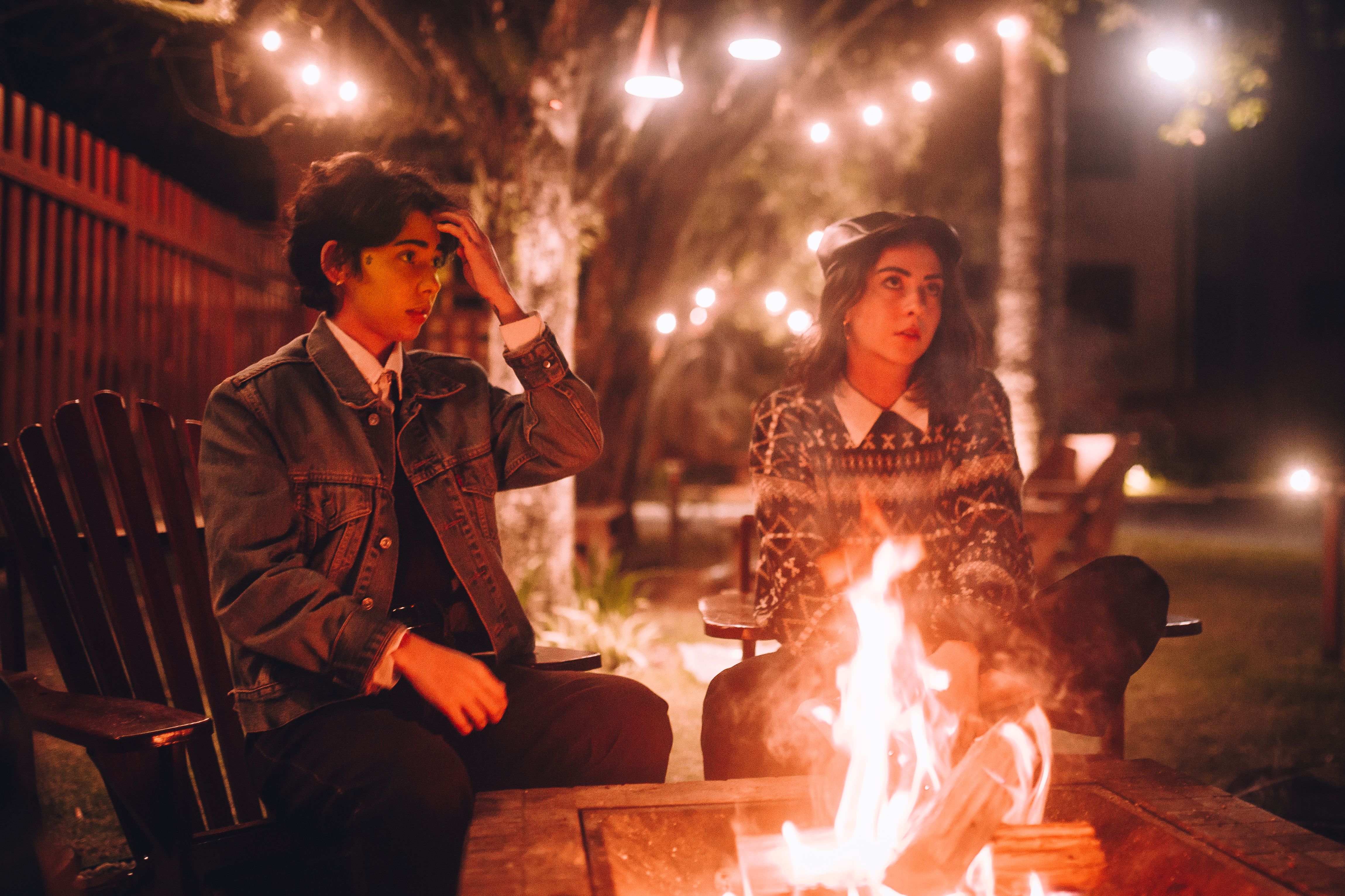 A cozy, personalized outdoor living space with a fire pit, string lights, and comfortable seating - Outdoor living trends