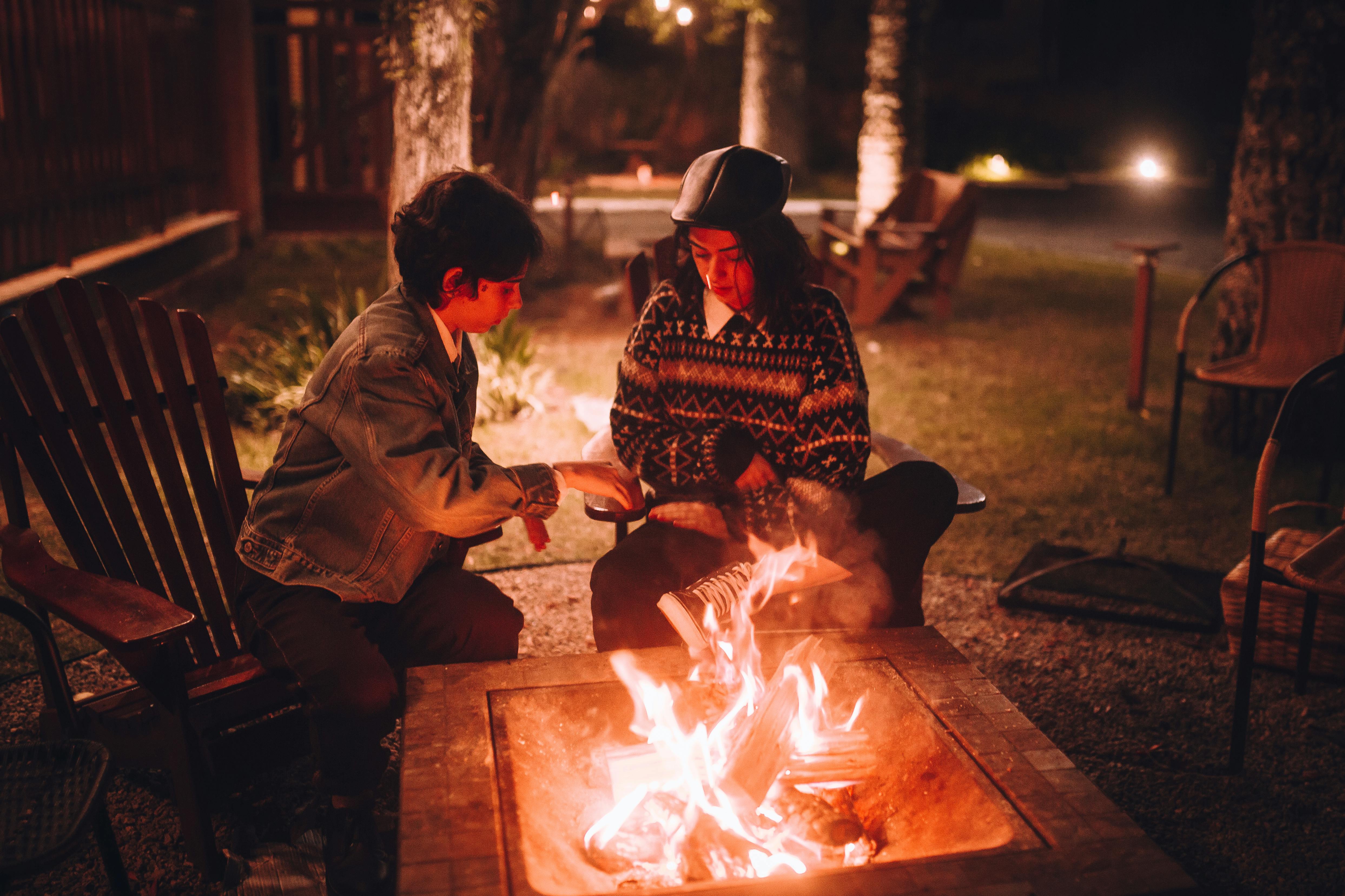 boy and girl sitting next to a bonfire