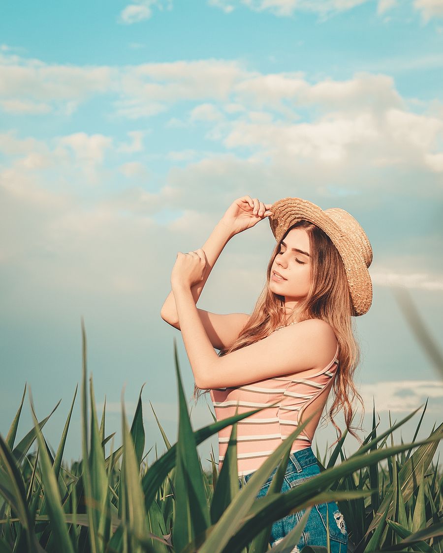 Woman in a straw hat standing in a sunny field