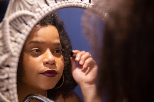 Photo of a Woman Applying Mascara on Her Eyelashes