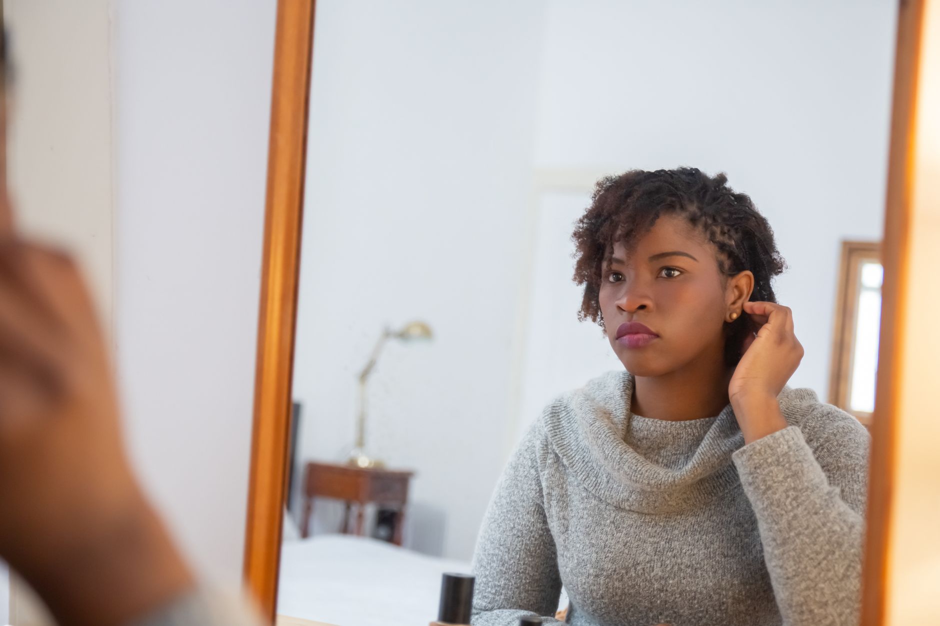 A woman looking at her reflection, considering her hair.