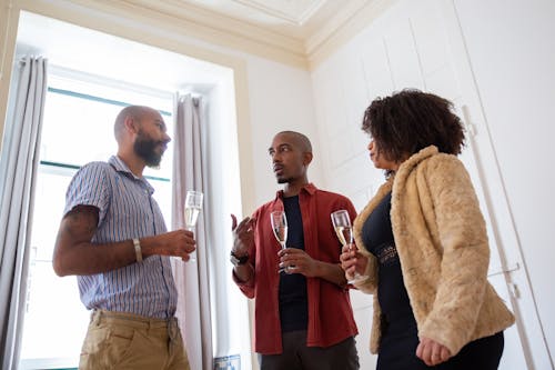 People Having Conversation While Holding Champagne Glasses