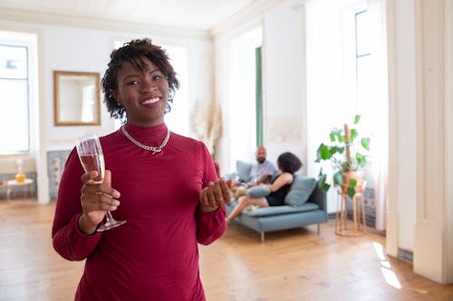 Close-Up Photo of a Woman in a Red Dress Holding a Champagne Glass