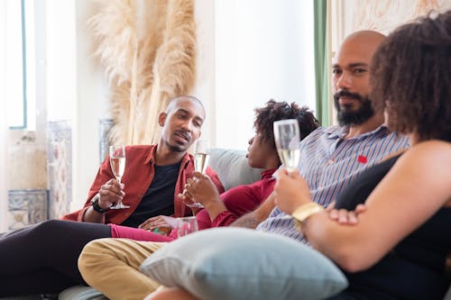 Men and Women Sitting on the Couch While Drinking Wine