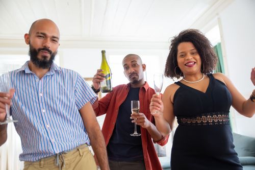 Free Three friends celebrate joyfully indoors with champagne and smiles, capturing a moment of happiness. Stock Photo