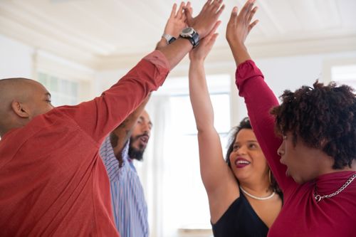 Free A group of cheerful friends high-fiving indoors, celebrating happiness and friendship. Stock Photo