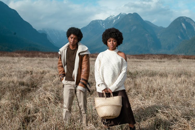 A Man And A Woman Standing On A Grass Field