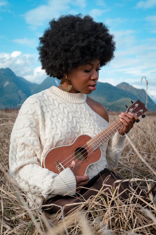 A Woman in a Knitted Sweater Playing the Ukulele