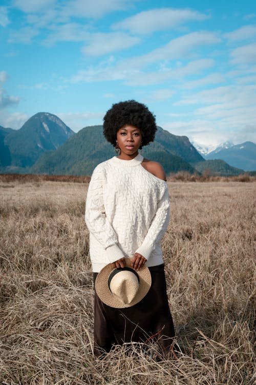 Photo of a Woman in a White Knitted Sweater Holding Her Hat