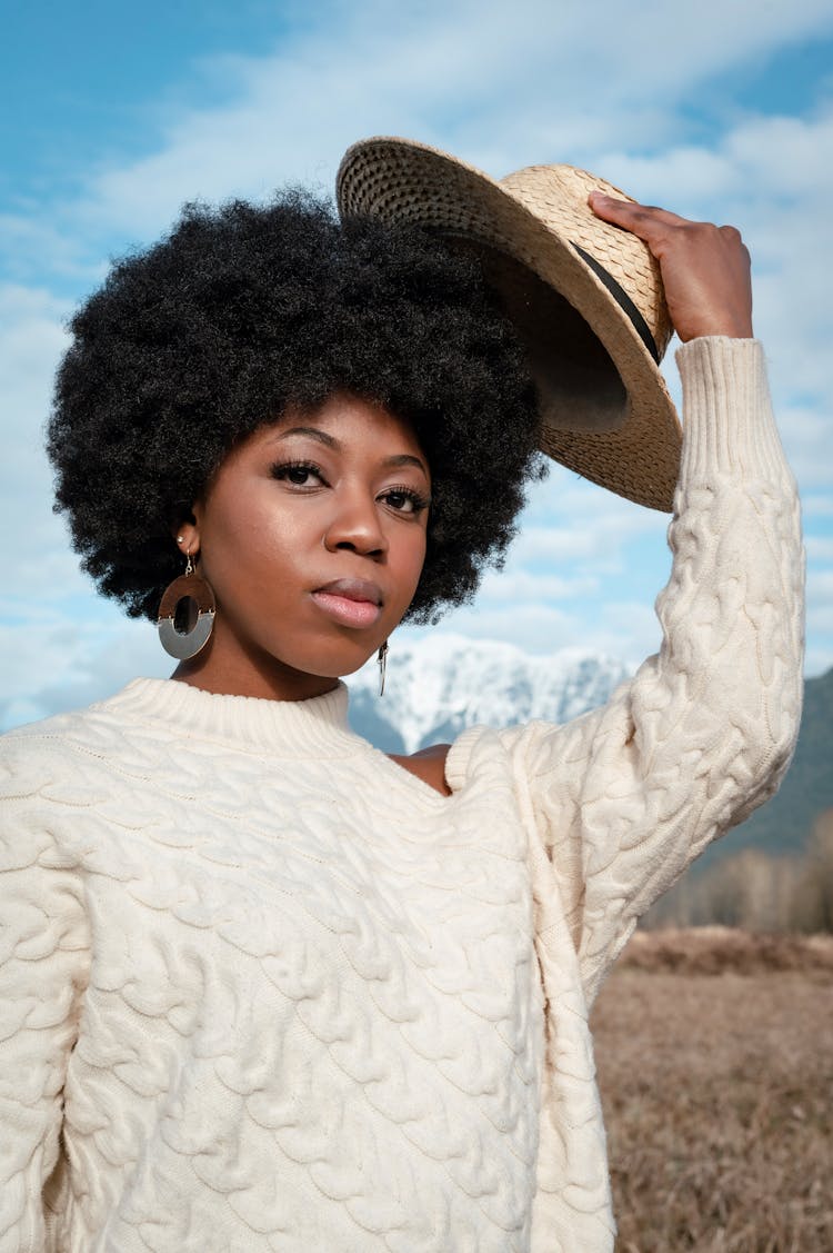 Close-Up Photo Of A Woman In A White Sweater Putting On Her Hat