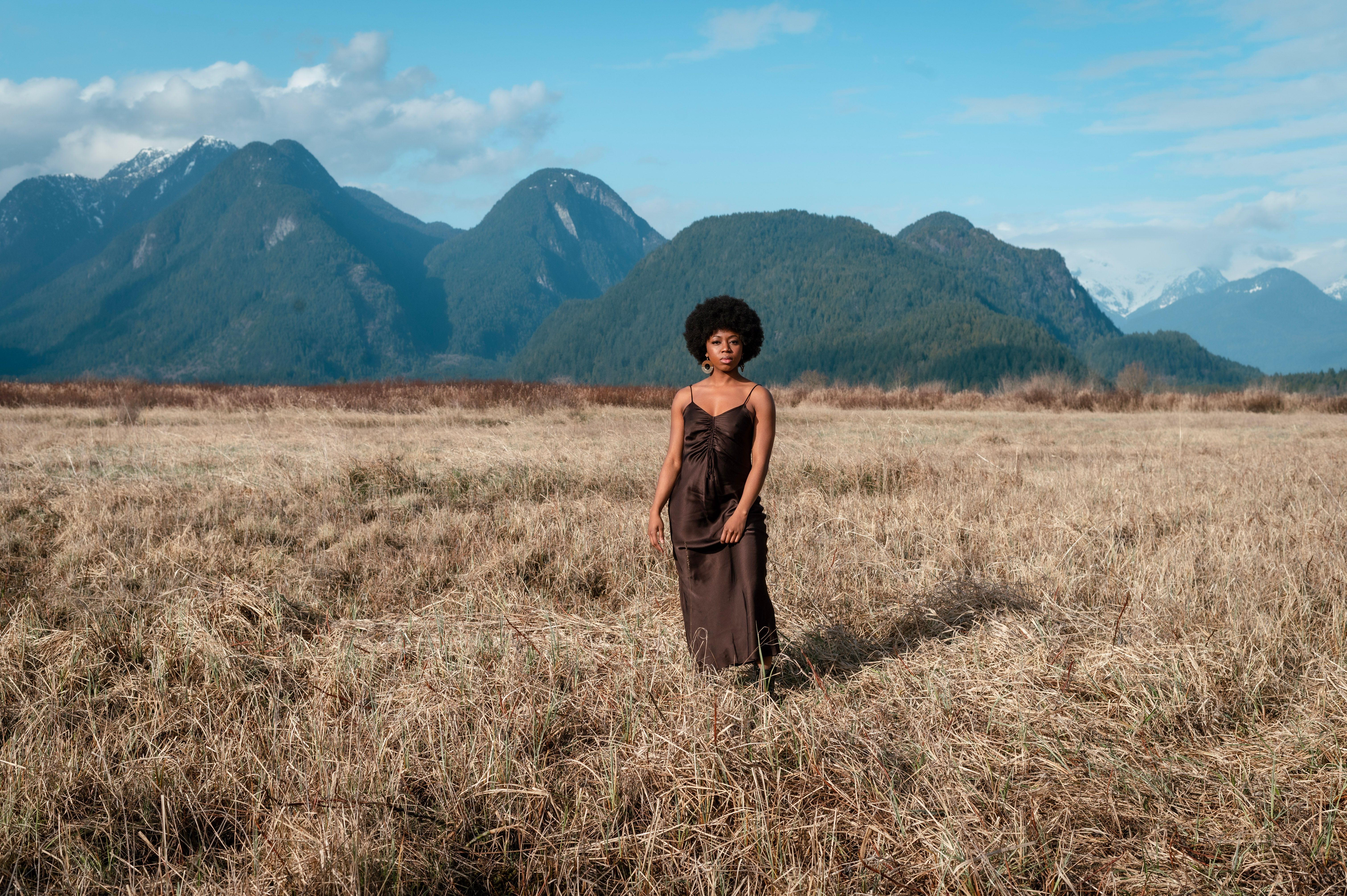 A Woman in Brown Dress Standing on Brown Grass Field · Free Stock Photo
