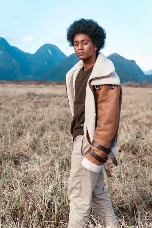 Woman in Brown Jacket Standing on Brown Grass Field