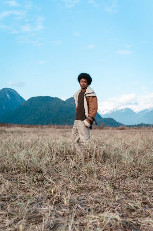 Man in Brown Jacket Standing on Brown Grass Field