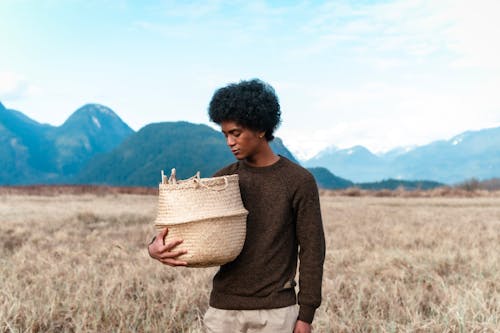 Man in Brown Sweater Carrying a Woven Basket