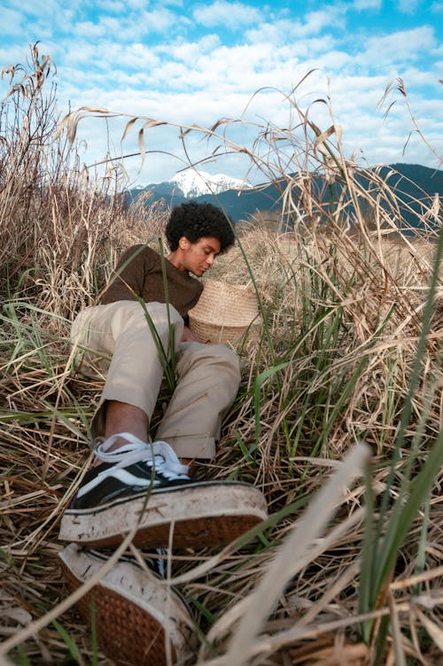 Man in Brown Sweater Lying on a Grass Field