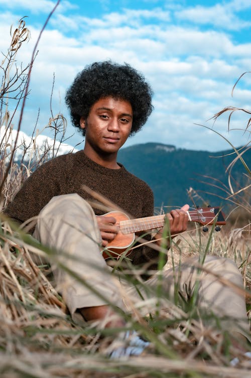 Man in Brown Sweater Playing the Ukulele