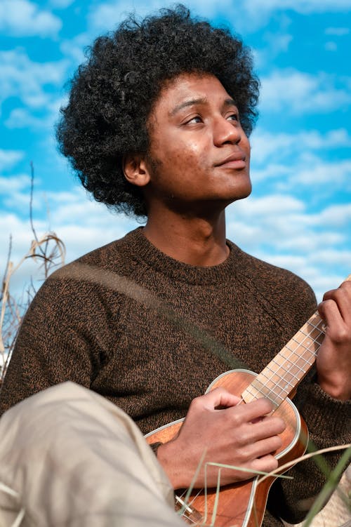 A Man in a Knitted Sweater Playing the Ukulele