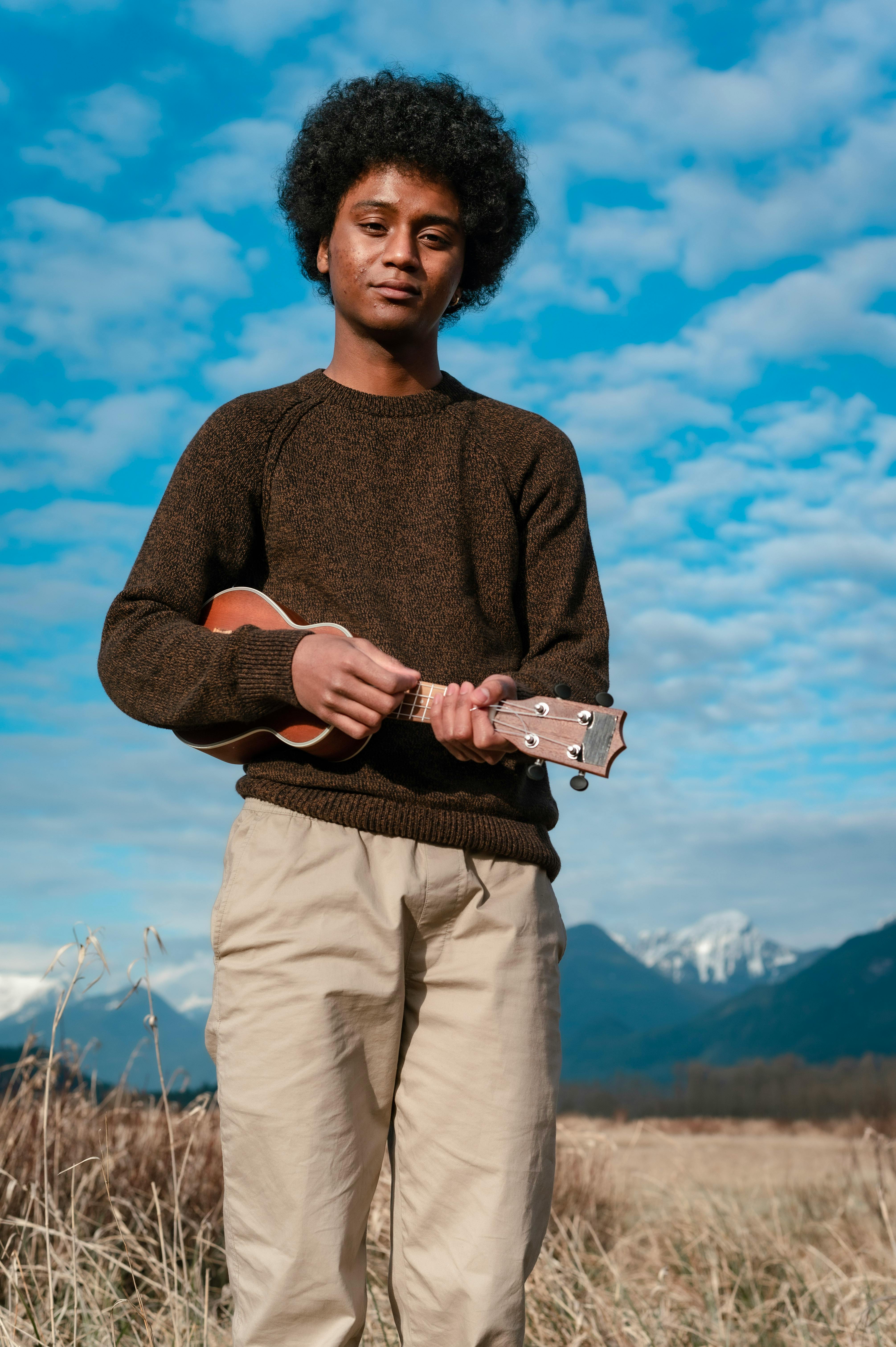 a man playing the ukulele in a field