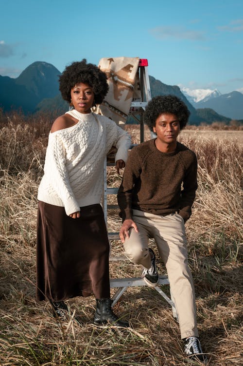 A Woman in White Sweater Standing Near the Man Sitting on the Ladder