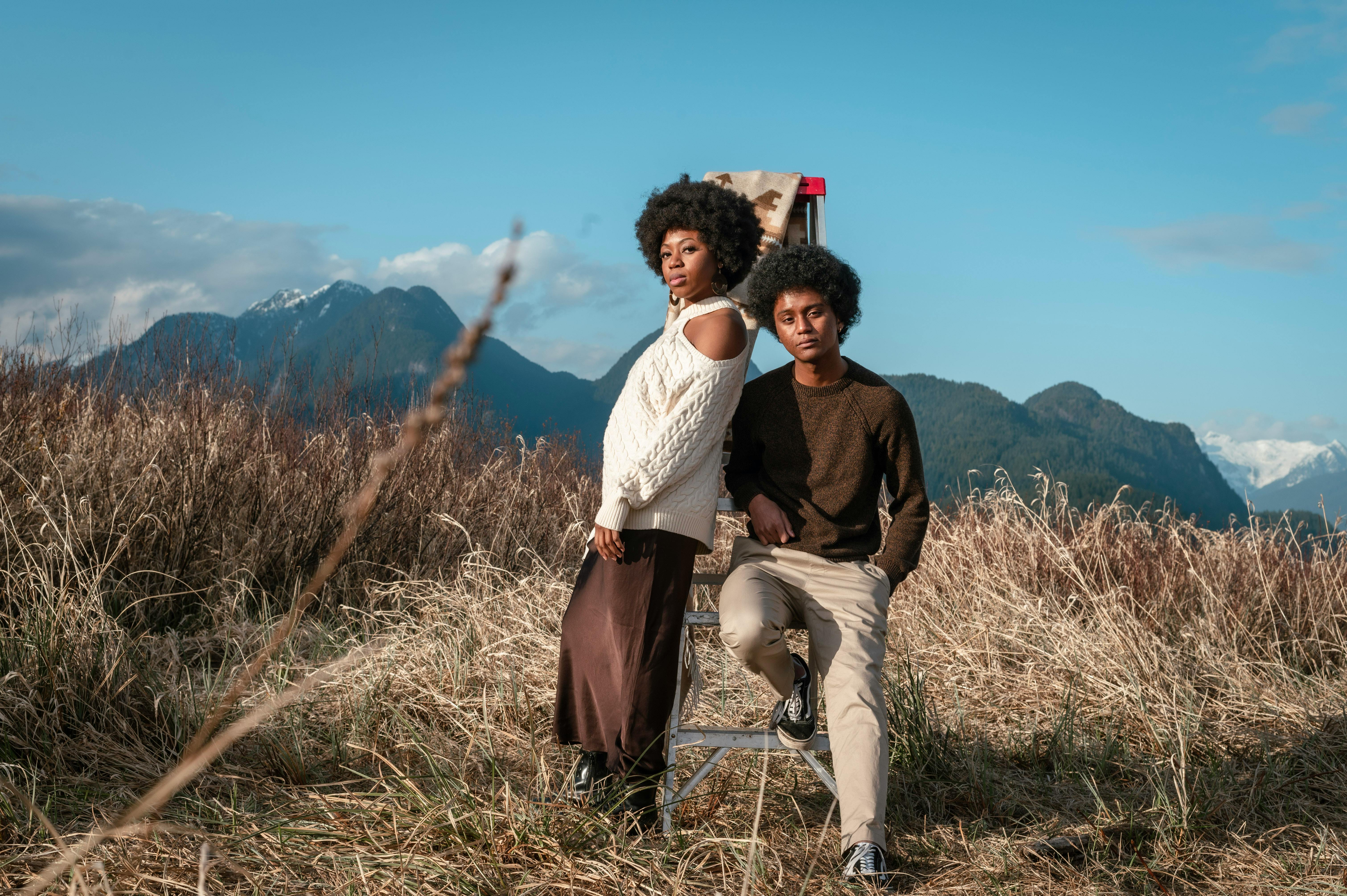 a man and a woman posing on a stepladder in a field