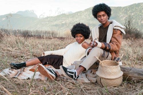 An Afro-Haired Man and Woman Sitting on a Grassy Field