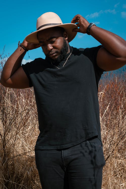 A Man in Black Shirt Standing on Brown Grass Field