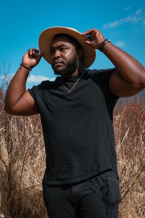 Free Fashionable African American man posing in a natural field setting. Stock Photo