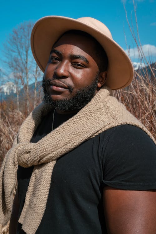 Photo of a Man in a Black Crew Neck Shirt Wearing a Beige Hat