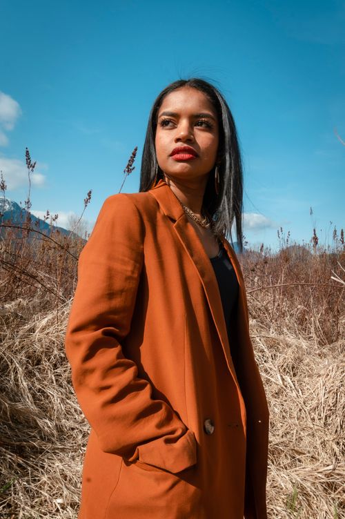 Free Stylish woman in a brown coat poses confidently in an autumn field. Stock Photo